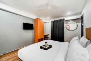 a hotel room with a white bed and a tv at Townhouse De Alphabet Tirupati in Tirupati