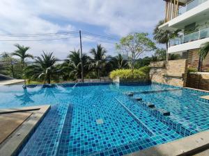 une grande piscine bleue à côté d'un bâtiment dans l'établissement Plus2 Condo by Khun Opor, à Ban Thung Thong