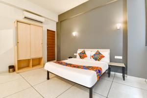 a bedroom with a large white bed with colorful pillows at FabHotel Kaviya in Ahmedabad