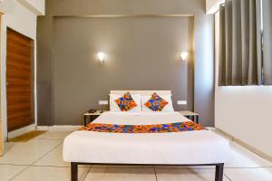 a bedroom with a white bed with colorful pillows at FabHotel Kaviya in Ahmedabad