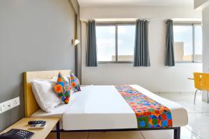a bedroom with a bed and a table and windows at FabHotel Kaviya in Ahmedabad