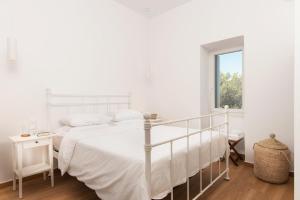 a white bedroom with a white bed and a window at Haroto Suites in Tripiti