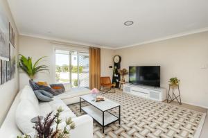 a living room with a white couch and a tv at Spacious newly redecorated 5BD Family Home in Brisbane