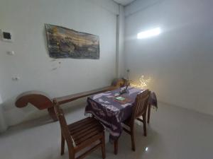 un comedor con mesa, sillas y una pintura en OYO 92644 Onong's Homestay en Tomohon