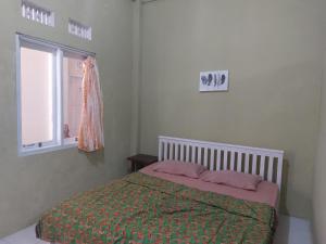 1 dormitorio con 1 cama con manta verde y ventana en OYO 92644 Onong's Homestay en Tomohon