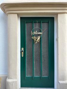a green door with a welcome sign on it at Altes Stadthaus mit Garten und Gewölbekeller in Stuttgart