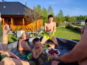a group of people sitting in a swimming pool at Nocowanie Olga i Oliwia in Okuninka