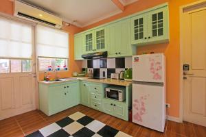 a kitchen with green cabinets and a white refrigerator at Capital O 92559 Sweet Peach House in Senggigi