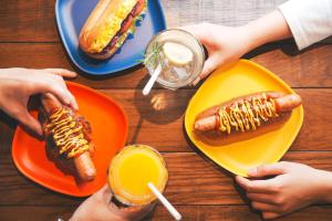 - une table avec deux assiettes de hot-dogs et une boisson dans l'établissement Anchor Hotel Fukuyama, à Fukuyama
