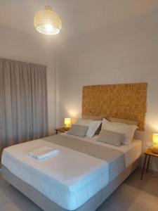 een slaapkamer met een groot wit bed met 2 lampen bij Irini pension in Platis Yialos Sifnos