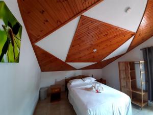 ein Schlafzimmer mit einem weißen Bett und einer Holzdecke in der Unterkunft La Source Self Catering in La Digue