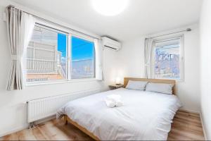 sypialnia z białym łóżkiem i 2 oknami w obiekcie THE SUN - Vacation STAY 14334 w mieście Sapporo