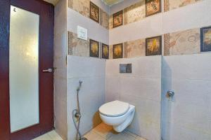a bathroom with a toilet and a wall with pictures at FabHotel Prime Surpin Palace in Kota