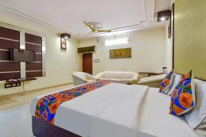 1 dormitorio con 1 cama blanca grande y TV en FabHotel Prime Surpin Palace, en Kota