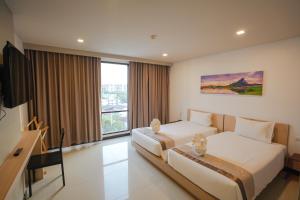 a hotel room with two beds and a television at Beston Pattaya - SHA Plus Certified in Pattaya South