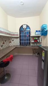 a kitchen with a counter with a chair and a window at Asha Home Stay Near Lucknow Airport in Lucknow