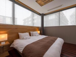 a bedroom with a large white bed with large windows at AYA Villa in Niseko