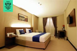 a hotel room with a bed and a television at Dafam Hotel Cilacap in Cilacap