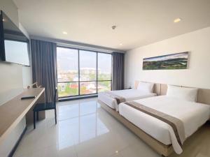 a hotel room with two beds and a large window at Beston Pattaya - SHA Plus Certified in Pattaya South