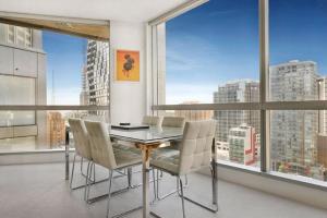 a dining room with a table and chairs and large windows at StayCentral - Melbourne Central in Melbourne