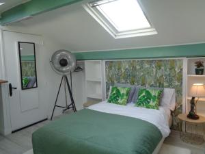Un dormitorio con una cama verde y blanca y un ventilador en vacances 34, en Le Crotoy