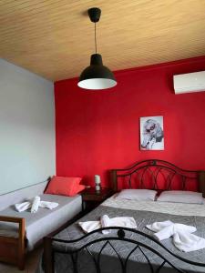 um quarto com 2 camas e uma parede vermelha em Cleopatra's Cozy Cottage em Keramoti
