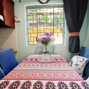 a table with a vase with purple flowers on it at Camelia Homestay in Hanoi