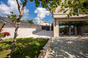a house with a tree in front of a driveway at House with pool Poli Stare nuoni in Žminj