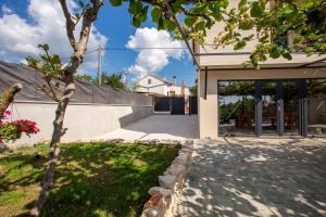 uma casa com uma árvore em frente a uma entrada em House with pool Poli Stare nuoni em Žminj