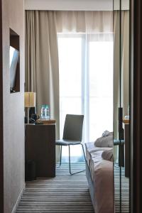 um quarto de hotel com uma cama, uma secretária e uma cadeira em Antonińska Resort SPA em Boszkowo