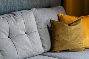 a gray couch with two pillows on it at Modern Apartment Górczyńska & Parking & Balcony by Renters Prestige in Poznań +14 photos