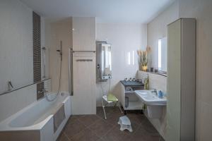 een witte badkamer met een bad en een wastafel bij 3 Raum FeWo Karl May, gehobene Ausstattung, Radebeul-Ost, 76qm in Radebeul