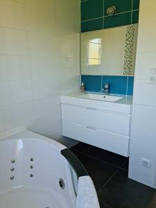 La salle de bains blanche est pourvue d'une baignoire et d'un lavabo. dans l'établissement Maison contemporaine aux portes des cevennes, à Alès