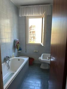 a bathroom with a tub and a toilet and a window at Immobile Vintage a Grado Pineta in Grado-Pineta