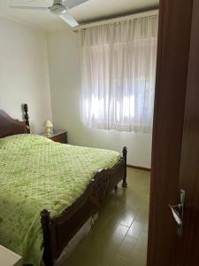 a bedroom with a bed with a green comforter and a window at Immobile Vintage a Grado Pineta in Grado-Pineta