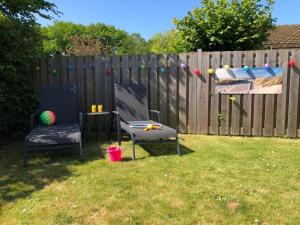 a backyard with two chairs and a table and a fence at Comfortabel 6-persoons huisje nabij strand, bos, duinen en stad in Warmenhuizen