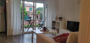 sala de estar con sofá, TV y balcón en ApartamentoCalellaClos, en Calella de Palafrugell