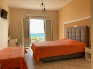 a bedroom with two beds and a large window at Diona Studios in Lourdata