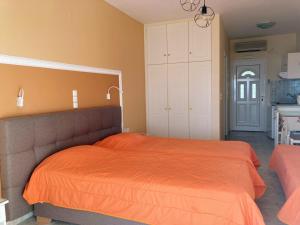 a bedroom with an orange bed and a kitchen at Diona Studios in Lourdata