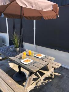 una mesa de picnic con dos platos de comida y una sombrilla en Comfortabel 6-persoons huisje nabij strand, bos, duinen en stad, en Warmenhuizen