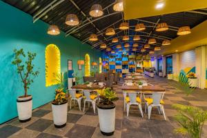 a colorful office with tables and chairs and plants at The Hosteller Goa, Candolim in Candolim