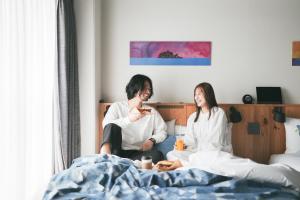 un homme et une femme assis dans un lit dans l'établissement Anchor Hotel Fukuyama, à Fukuyama