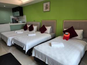 2 camas en una habitación con paredes verdes en The Viana Apartment V, en Kota Bharu