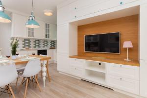 uma cozinha com uma mesa de jantar e uma televisão de ecrã plano em Italian-style Apartment in the "Tesoro Gardens" by Renters em Gdynia