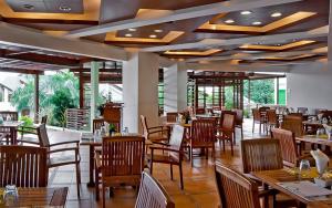 Acuatico Beach Resort & Hotel Inc. في سان خوان: مطعم بطاولات وكراسي خشبية ونوافذ