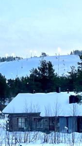 a house with a snow covered roof in a field at Nilimukka in Levi