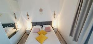 a small bedroom with a bed with two yellow pillows at AJP Nova3 Lux Apartament in Szczecin