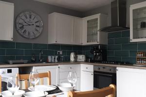 a kitchen with a table and a clock on the wall at Ty Fi in Menai Bridge