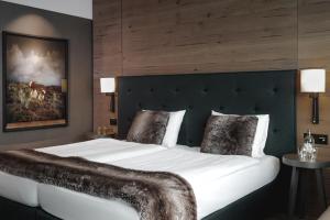 a bedroom with a large white bed with a headboard at AMERON Davos Swiss Mountain Resort in Davos