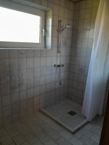 y baño alicatado con ducha y ventana. en 2 bedroom 1 bath apartment, en Kruså